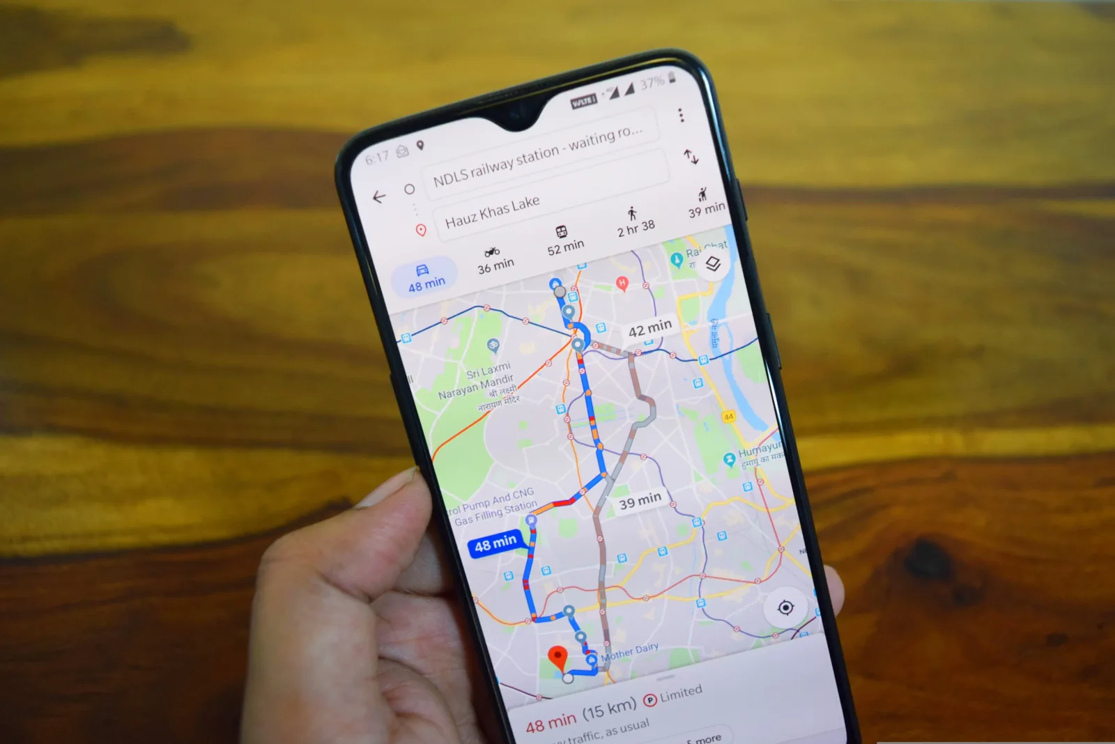 A hand holding a phone displaying Google Maps and route options